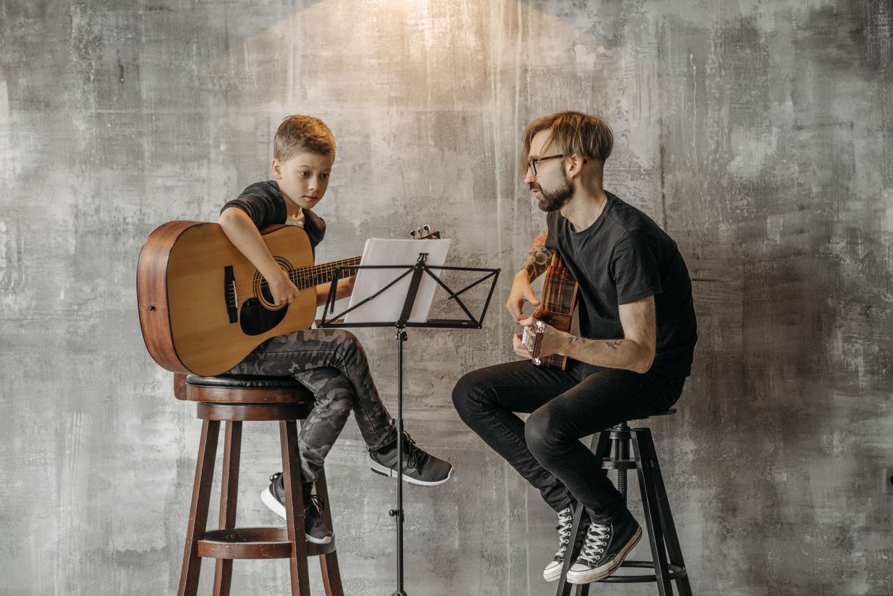 a music teacher taking a guitar lesson for a young boy
