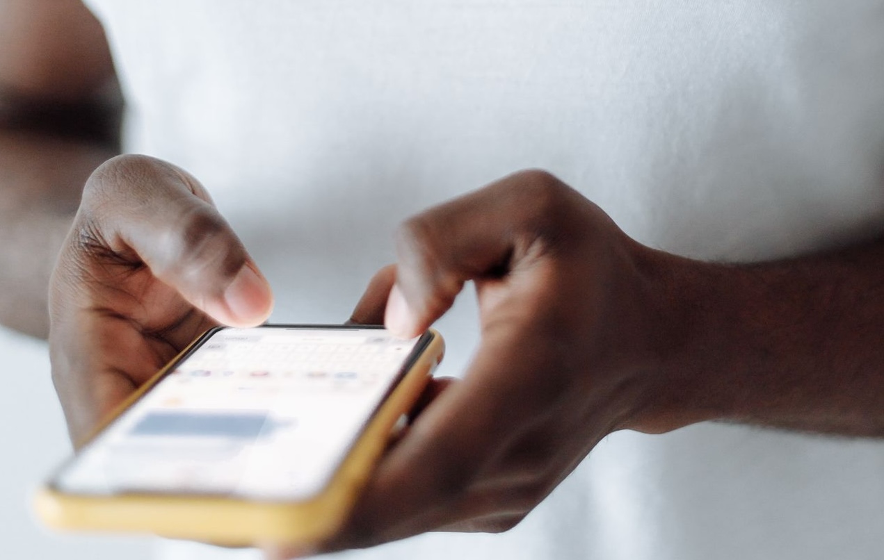 Close-up shot of a person texting on a smartphone, wearing a white t-shirt.