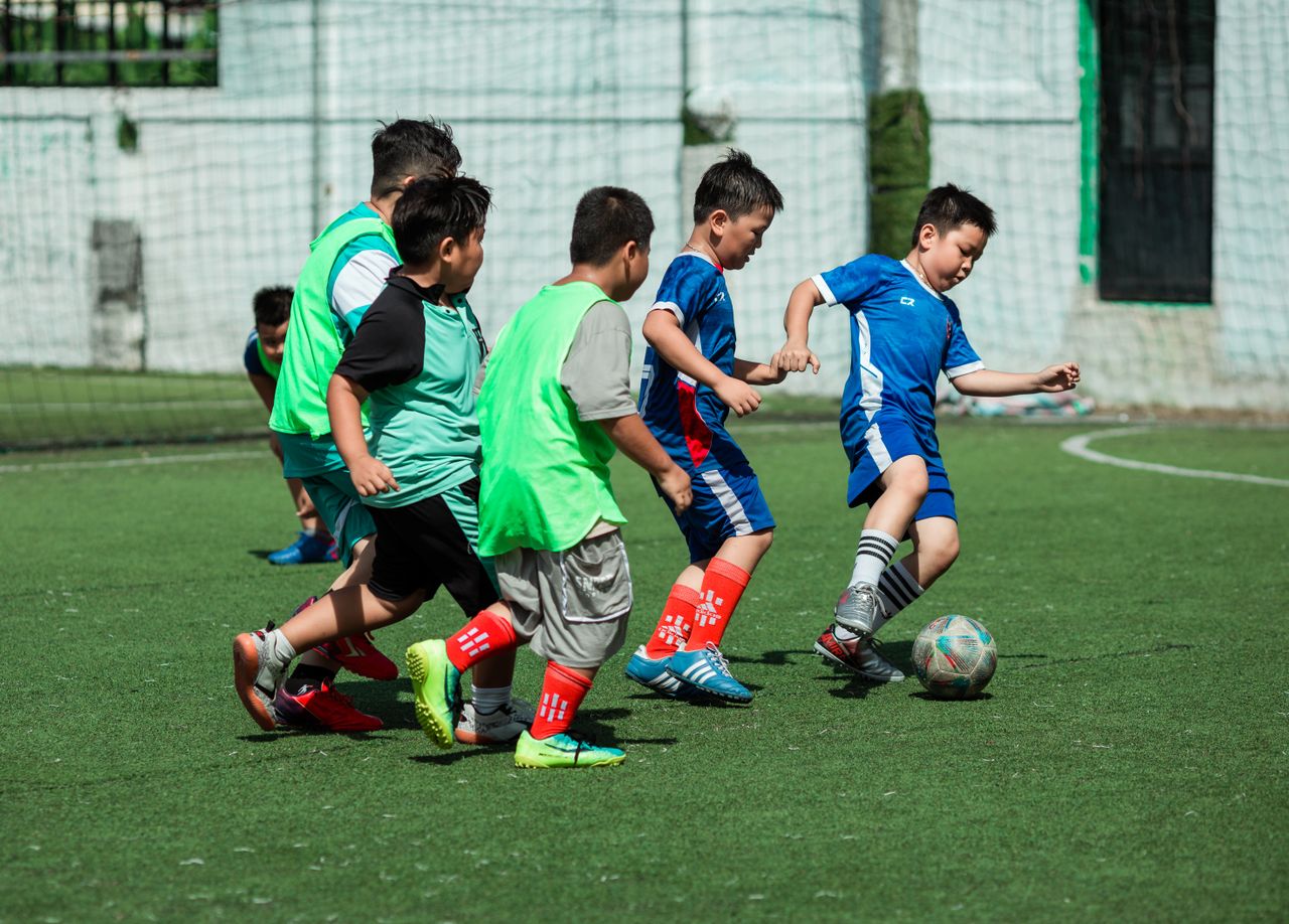 A group of boys energetically playing soccer outdoors on a sunny day