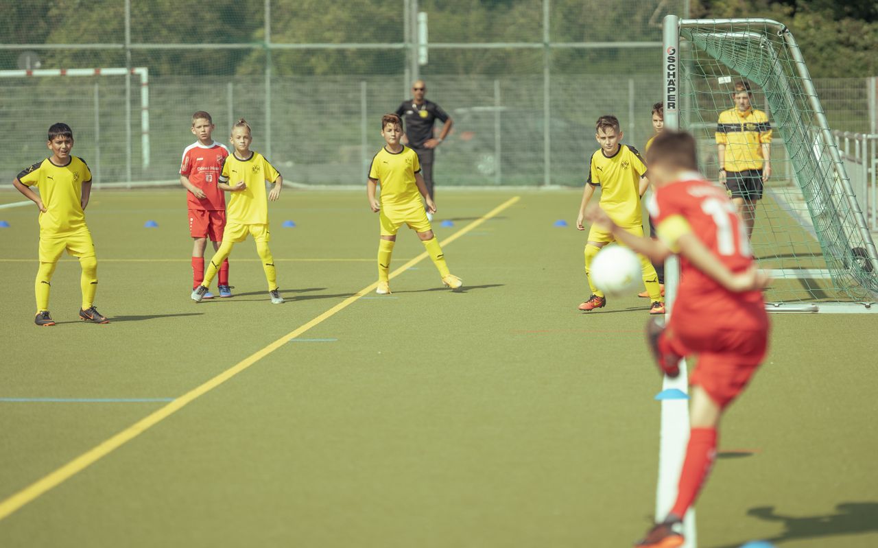 a youth soccer training session on an outdoor green field with players in yellow and red uniforms