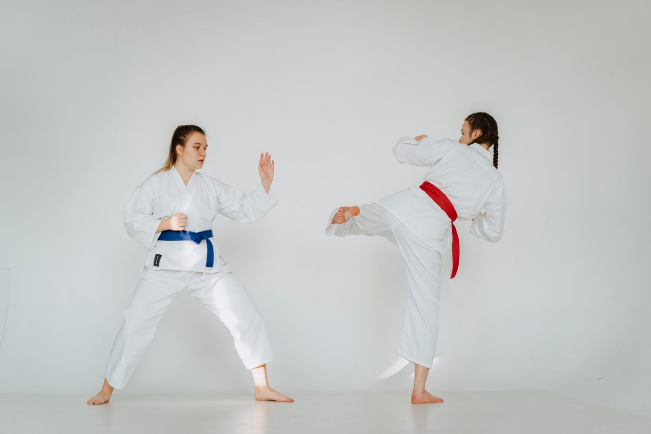 Karate sparring practice with two young women showcasing skill and technique in traditional attire.