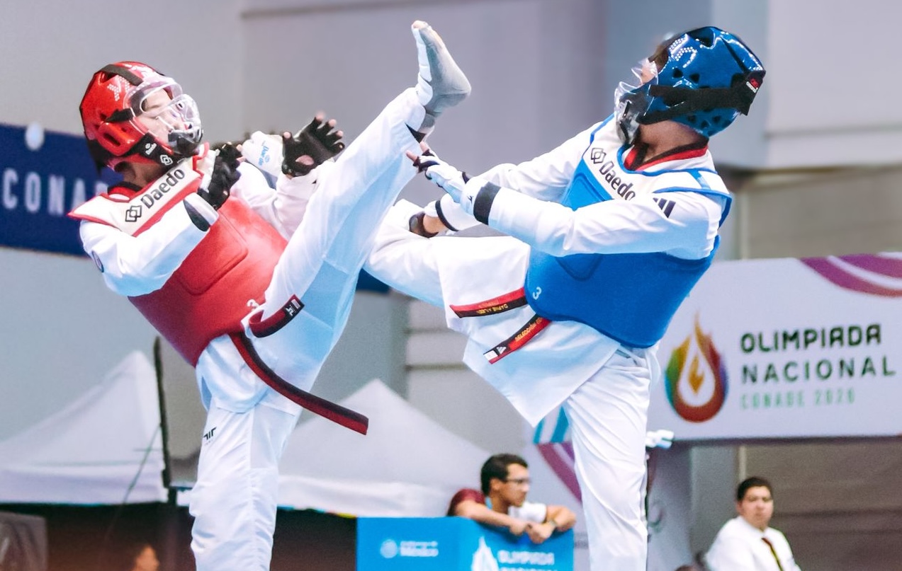 Two athletes in intense Taekwondo match at a live event.