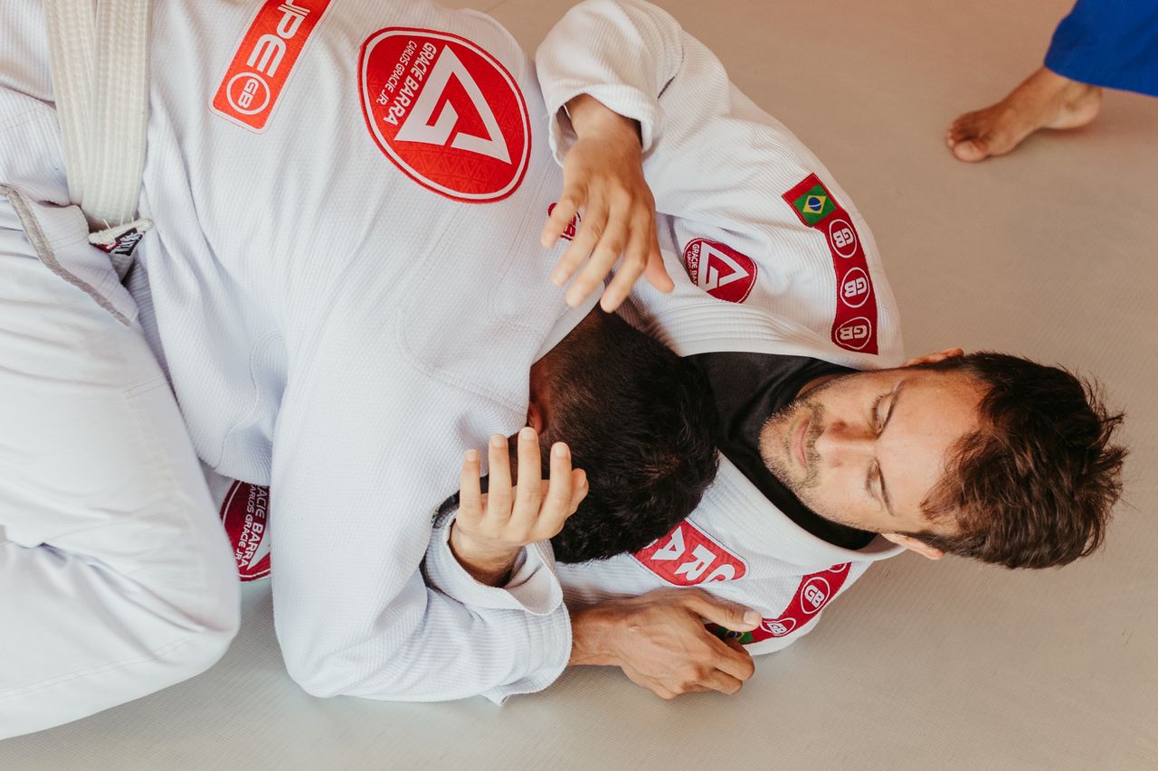 Two men engaging in a Brazilian Jiu-Jitsu match, showcasing grappling techniques from a top view perspective.