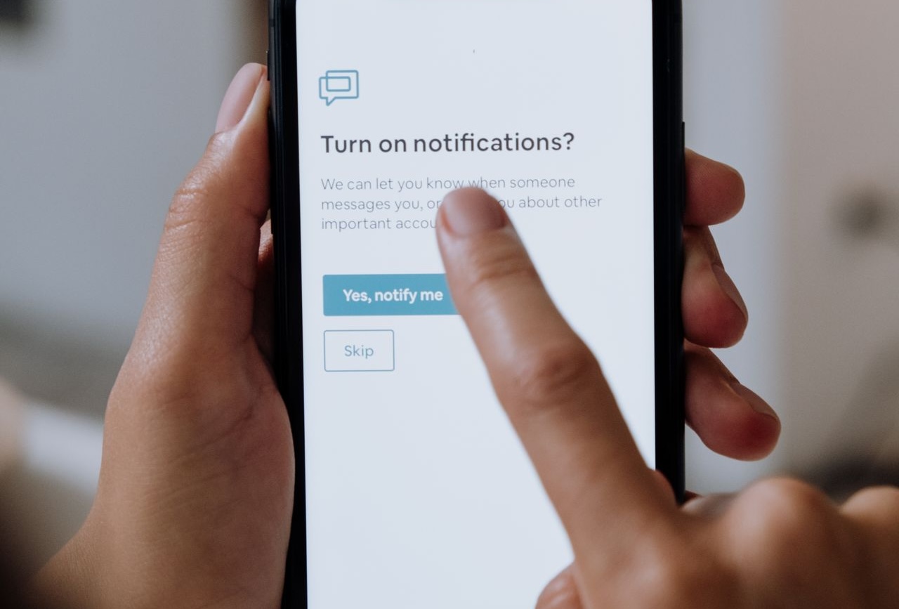 Close-up of hands using a smartphone for digital notification setup.