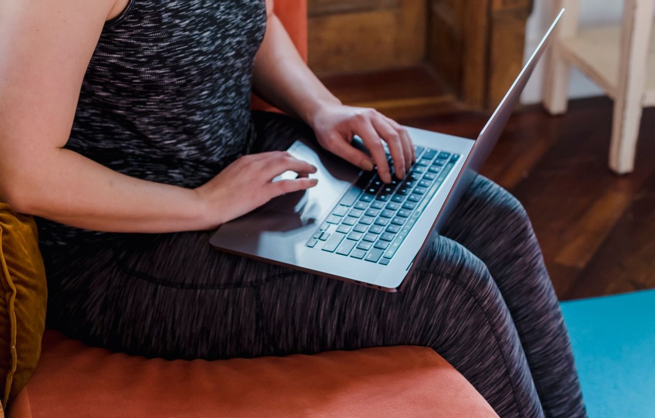 Young woman using a laptop at home, sitting on a sofa