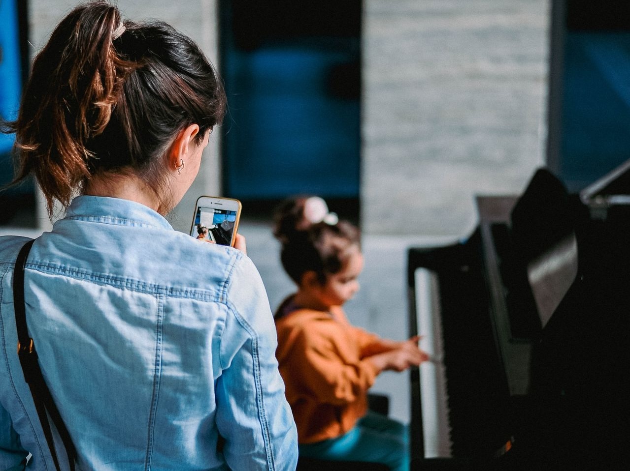 a mother records her daughter playing the piano on her phone