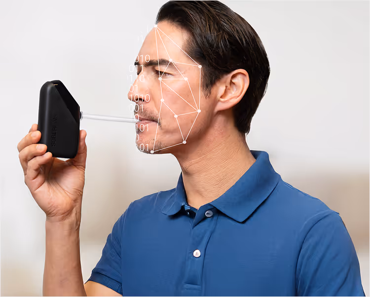 A man blowing into a Soberlink device