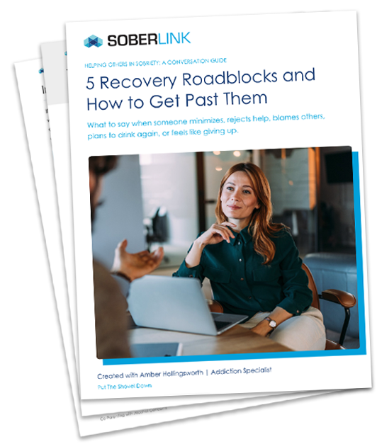 Cover page of a guide titled '5 Recovery Roadblocks and How to Get Past Them' by Soberlink, featuring a photo of a woman attentively listening to a man during a conversation at a table with a laptop.