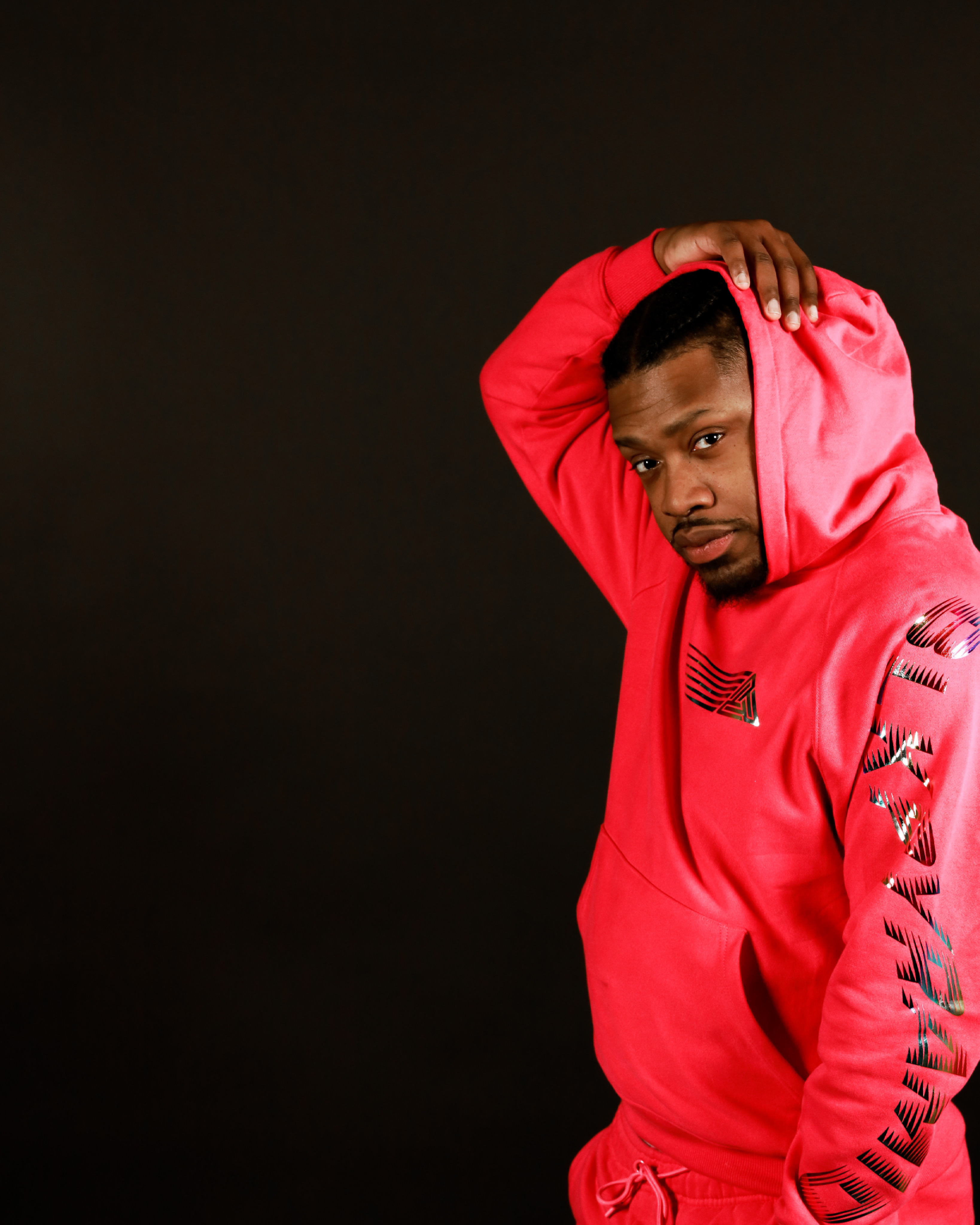 A close up of DJ Shaheed Ali in front of a red, orange and yellow mural.