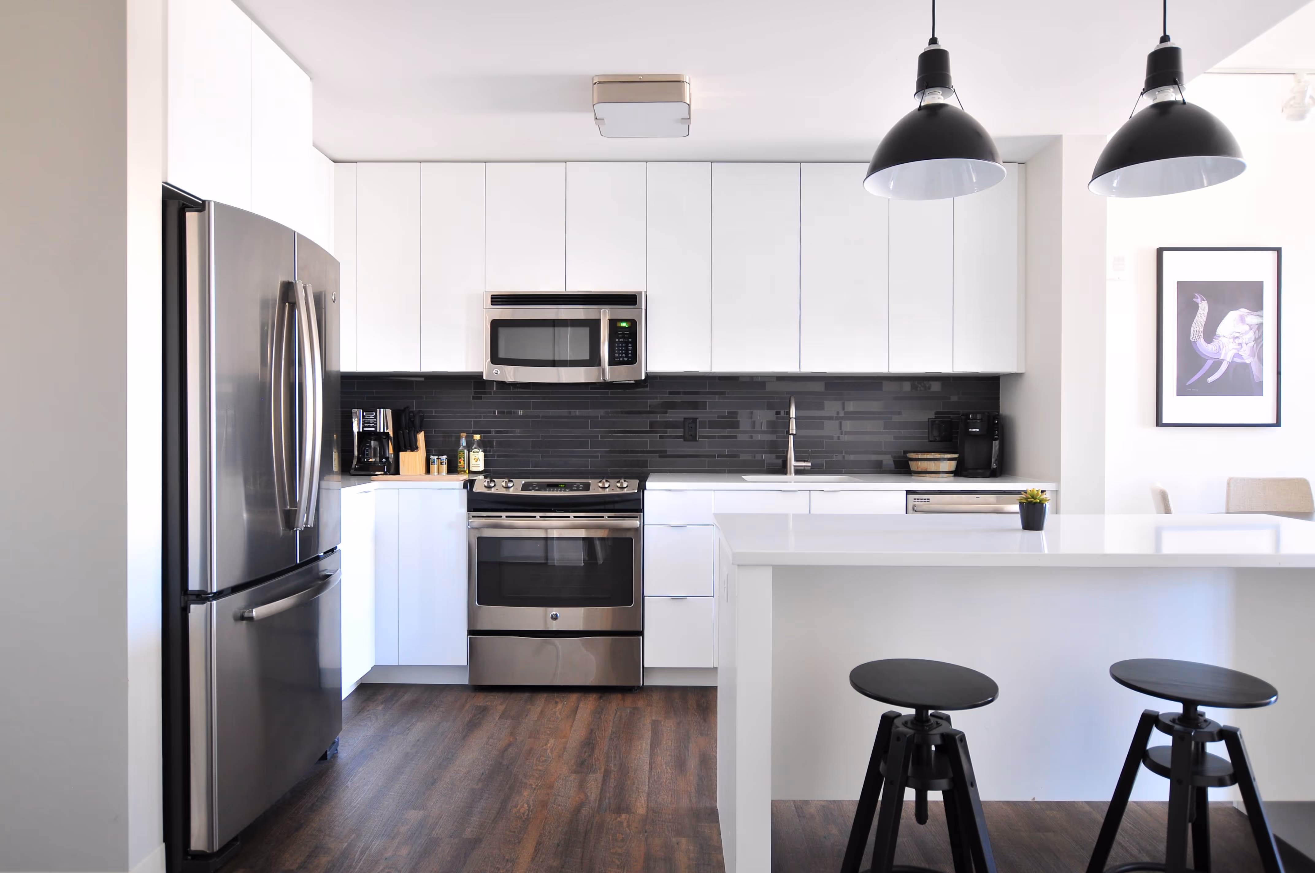 White modern kitchen with stainless steel appliances.