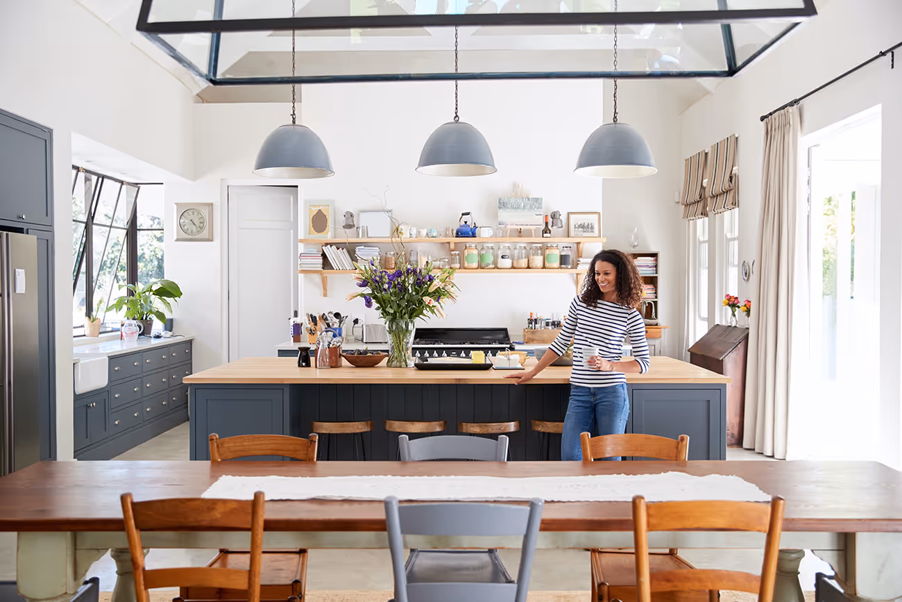 Woman leaning on kitchen island in open plan home.