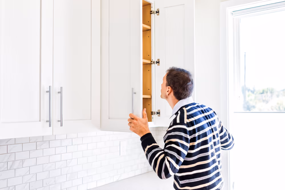 Man looking inside cabinet during home inspection.