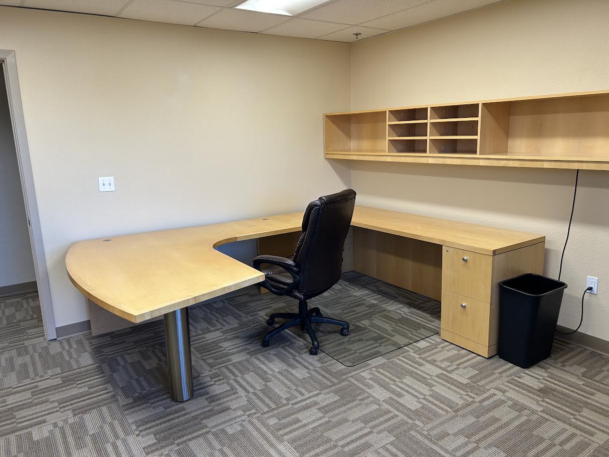 An image of Atwood Business Park's Suite 213, with included desk and cabinets, facing the door.