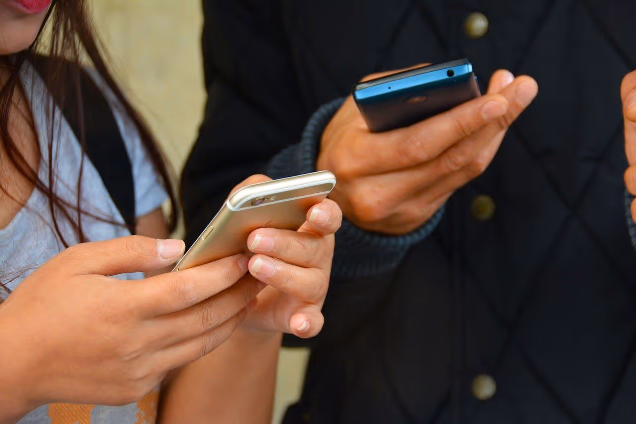 Photo of two teens looking at their cell phones.