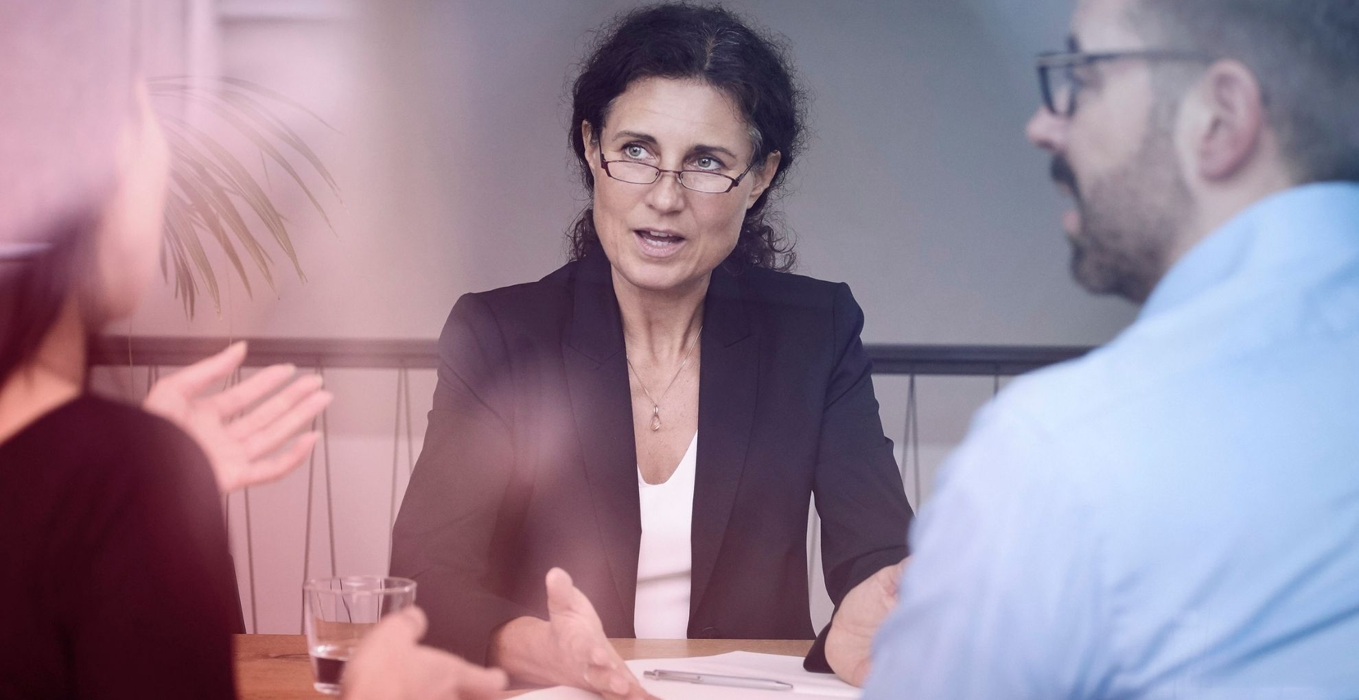 Vrouw legt iets uit aan man en vrouw tegenover haar aan tafel