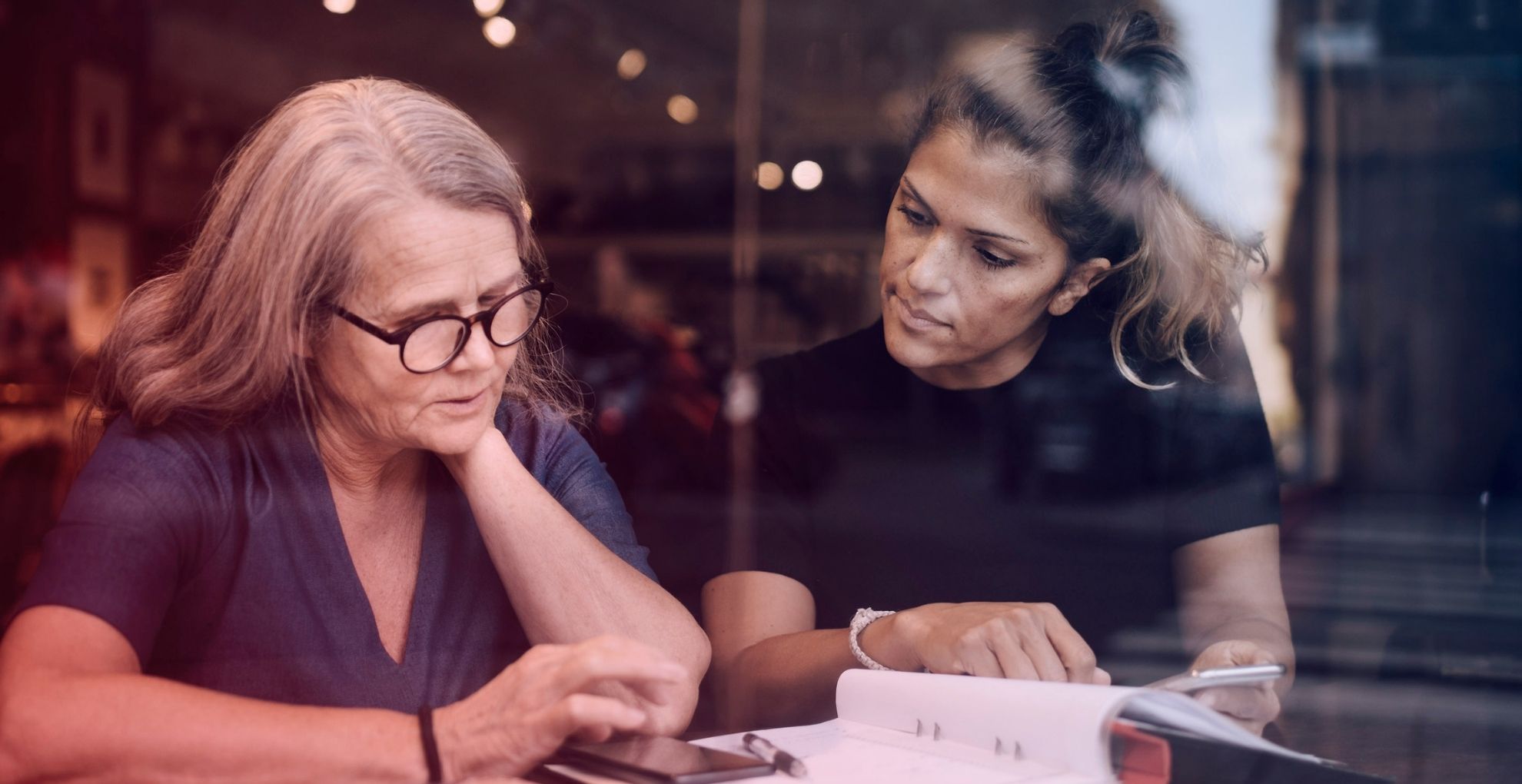 Twee vrouwen samen aan tafel met papieren en rekenmachine