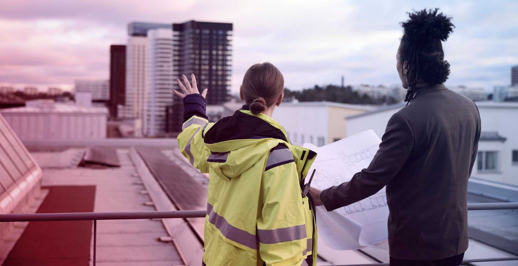 Man en vrouw staan met tekening bij bouwproject