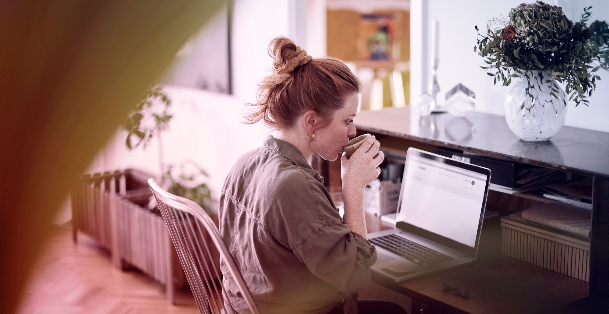 Vrouw met koffie achter de laptop