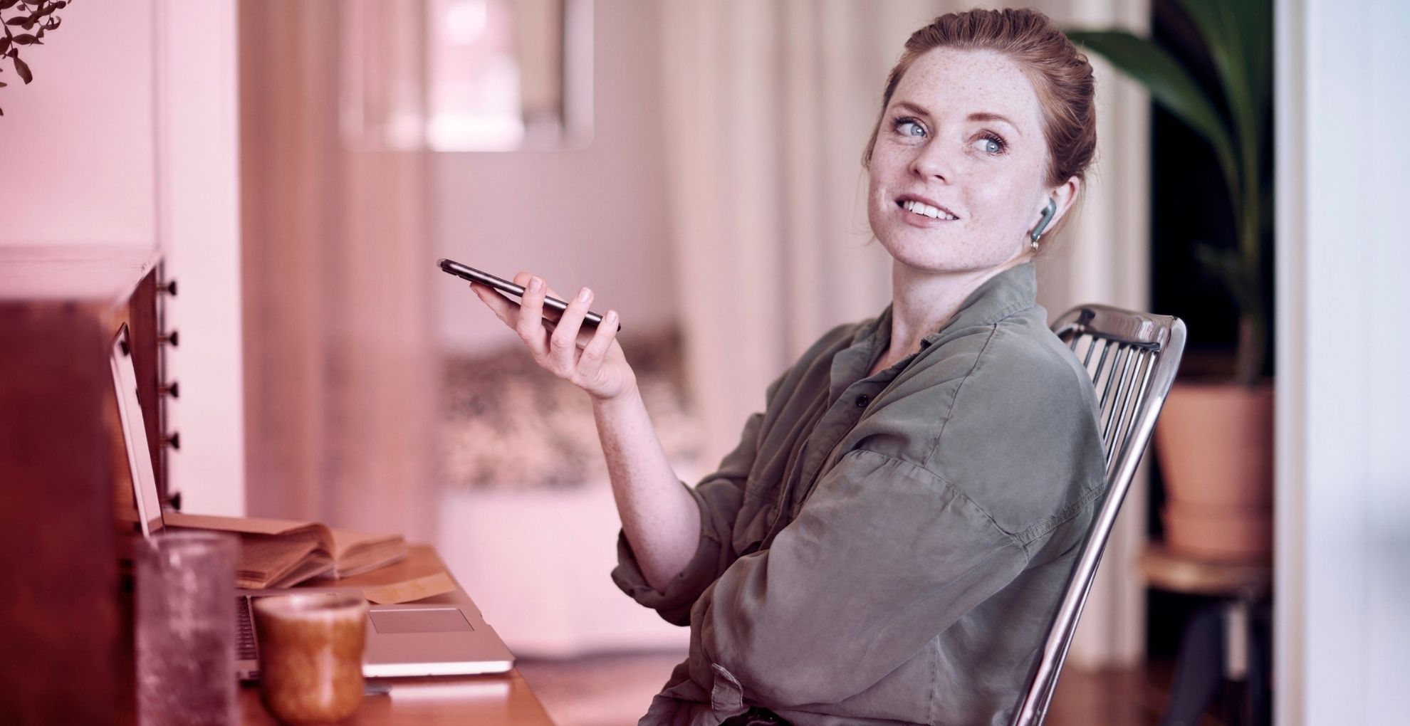 Jonge vrouw achter laptop met telefoon
