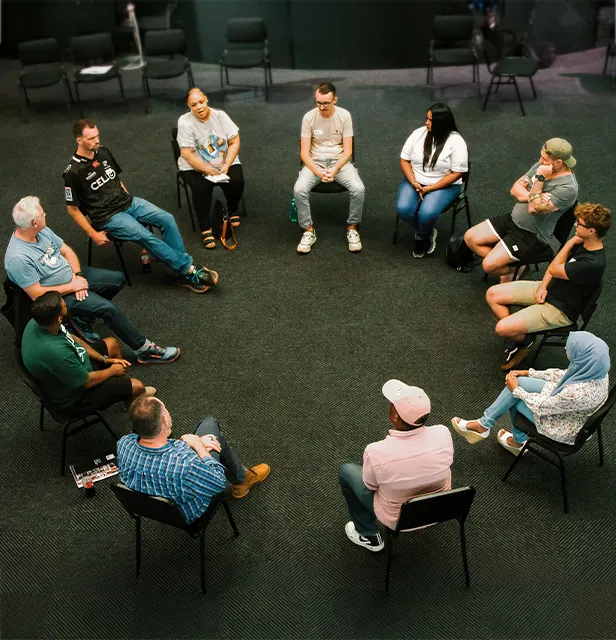 A group of people seated in a circle, actively discussing and interacting with one another.