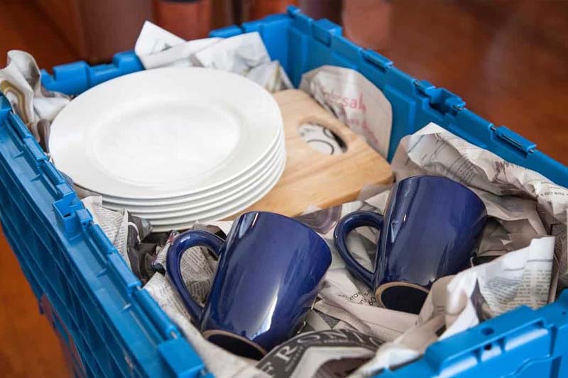 Plates and mugs packed in an open blue Bin It bin