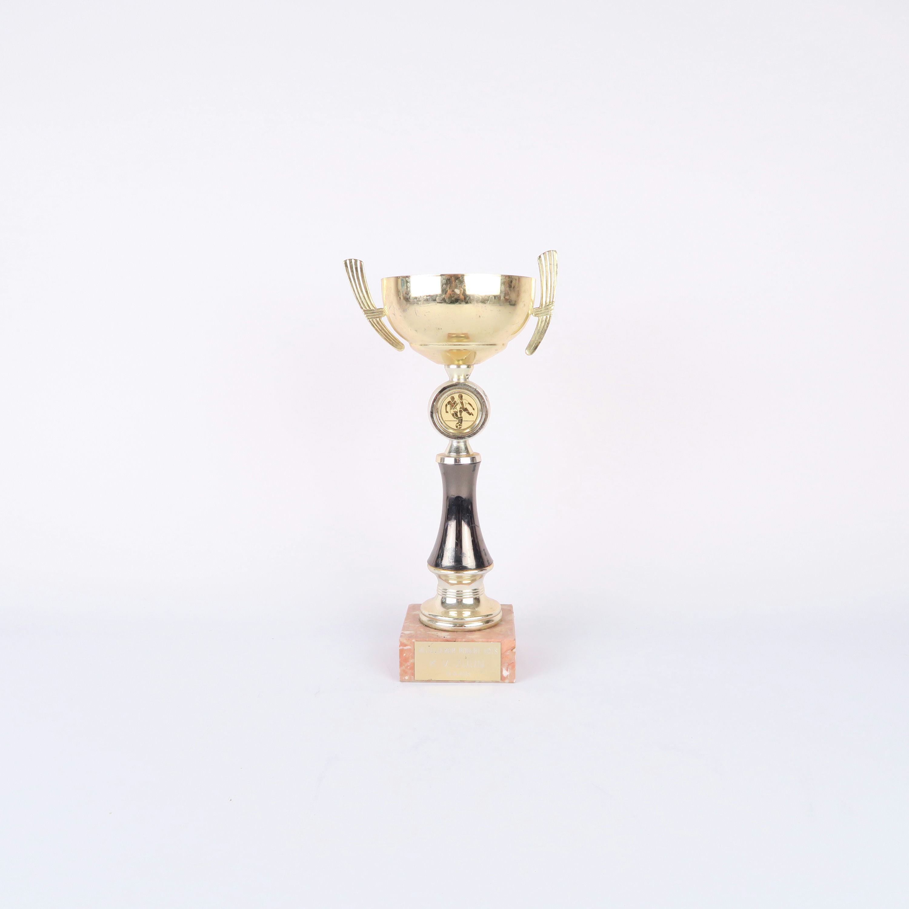 coupe dorée de football et socle en pierre orangée