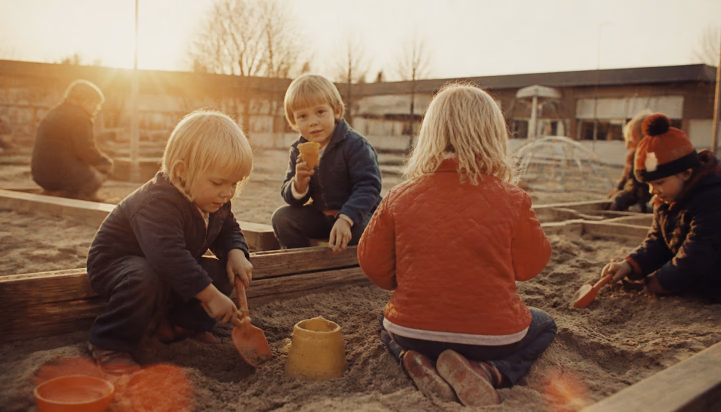 Mamma med barn i knät på en veranda vid ett gult trähus