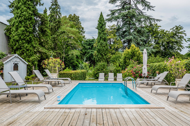 A wide angle shot of an outside swimming pool with trees in the background
