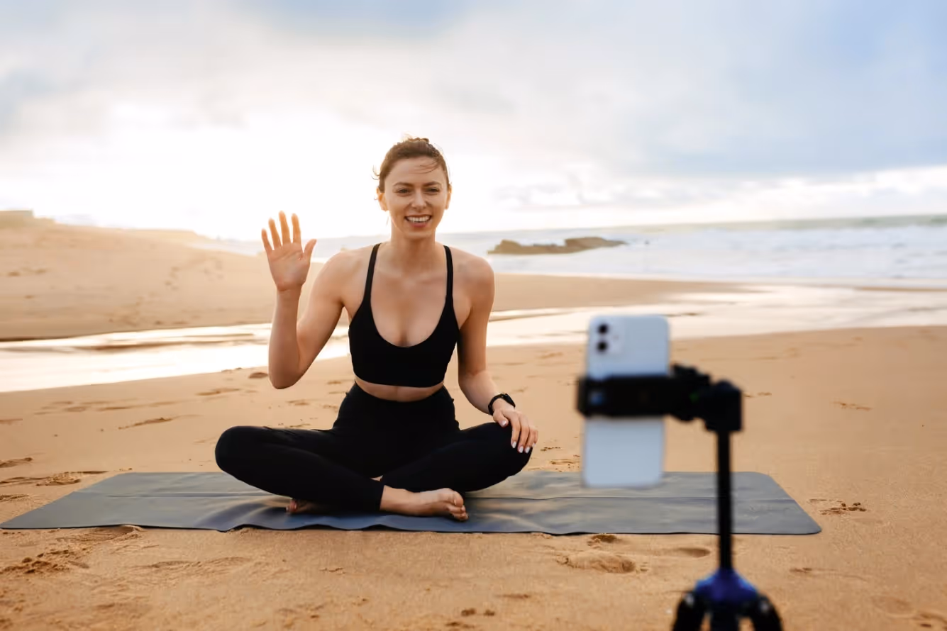 An online fitness coach at the beach livestreaming a class