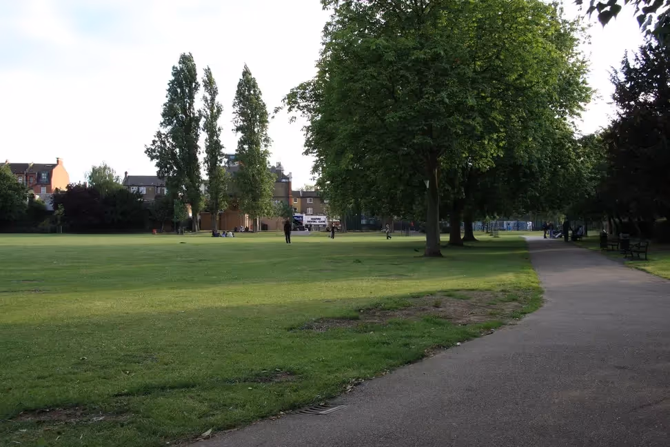Two trees and a wide landscape of Kilburn Grange Park.