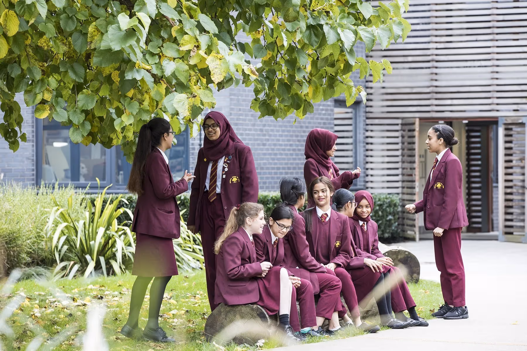 Girls dressed in burgundy uniform standing outside Mulberry School for Girls in Shadwell, East London.