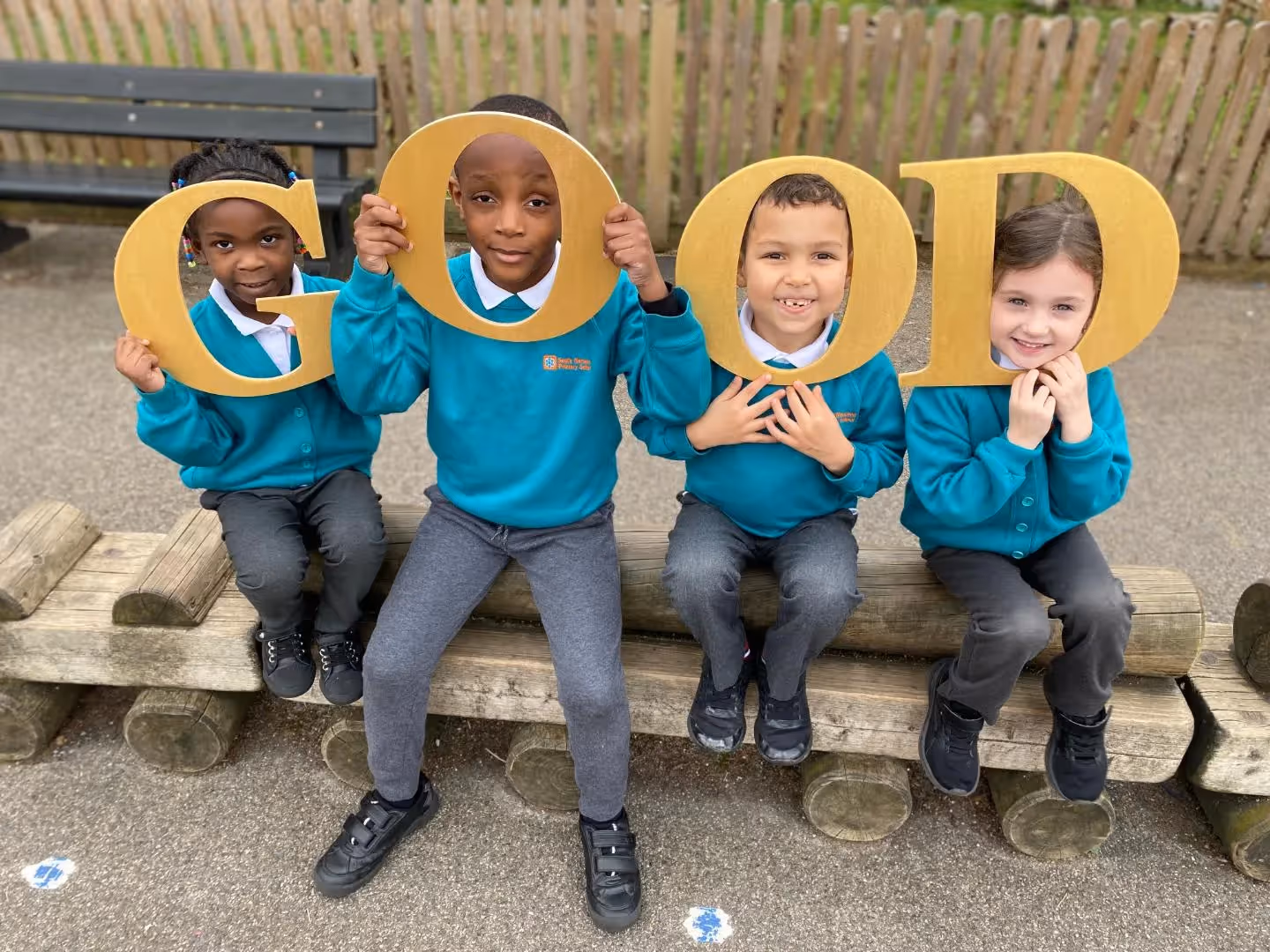 A group of children in uniform surrounding the head teacher at South Norwood Primary.