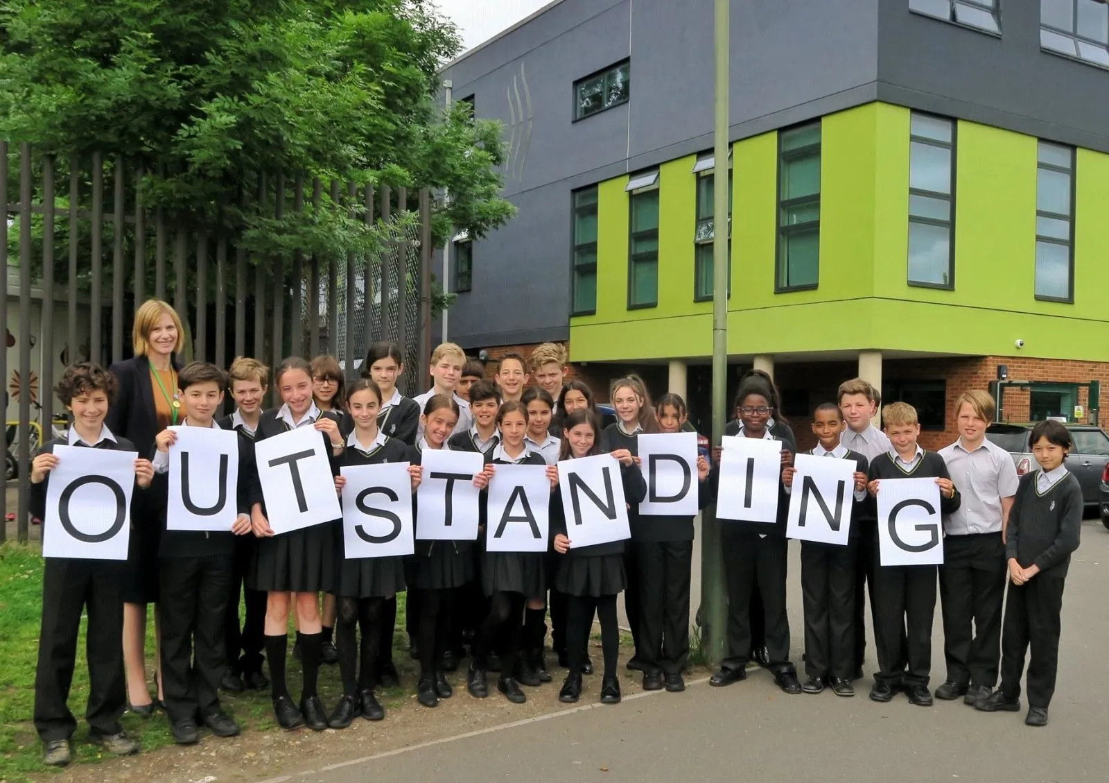 High school aged students in uniform walking and smiling on campus at The Archer Academy in East Finchley.