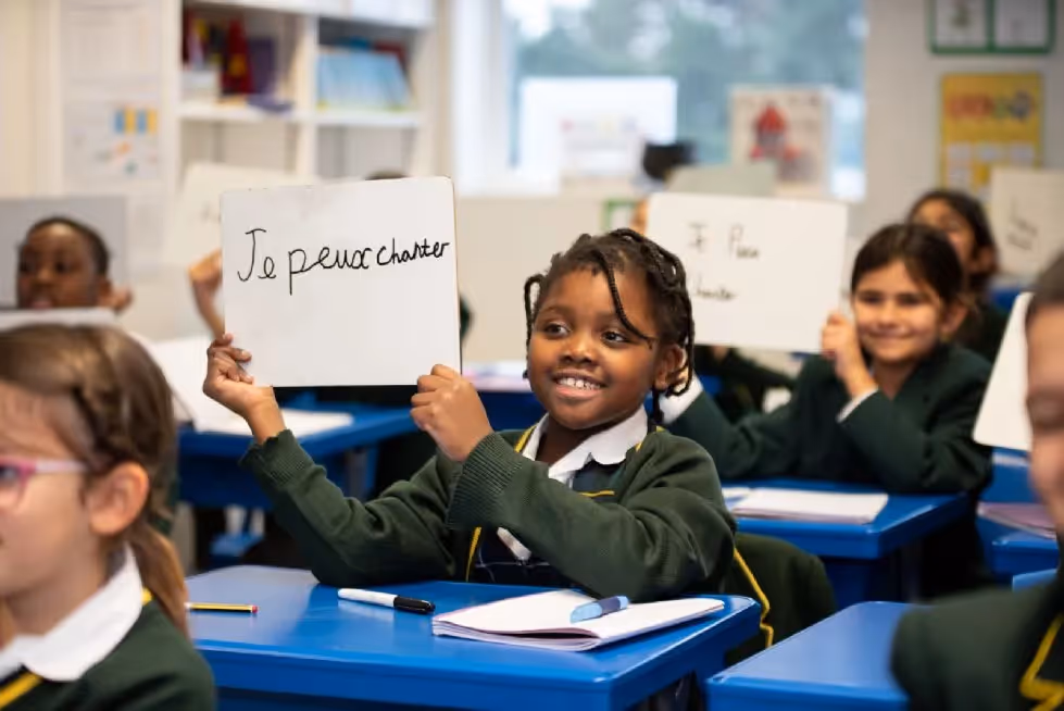 Two girls in uniform laying on the grass at Holland House School in Edgware.