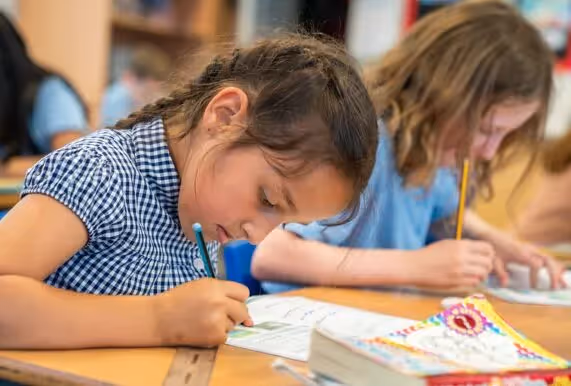 Junior aged students in a classroom enjoying themselves with big smiles on their faces.