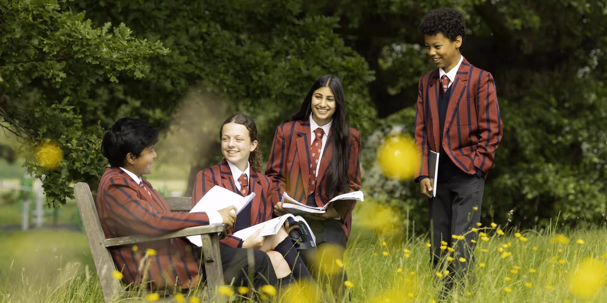 A group of children with the headteacher holding up exam results at Mill Hill County School.