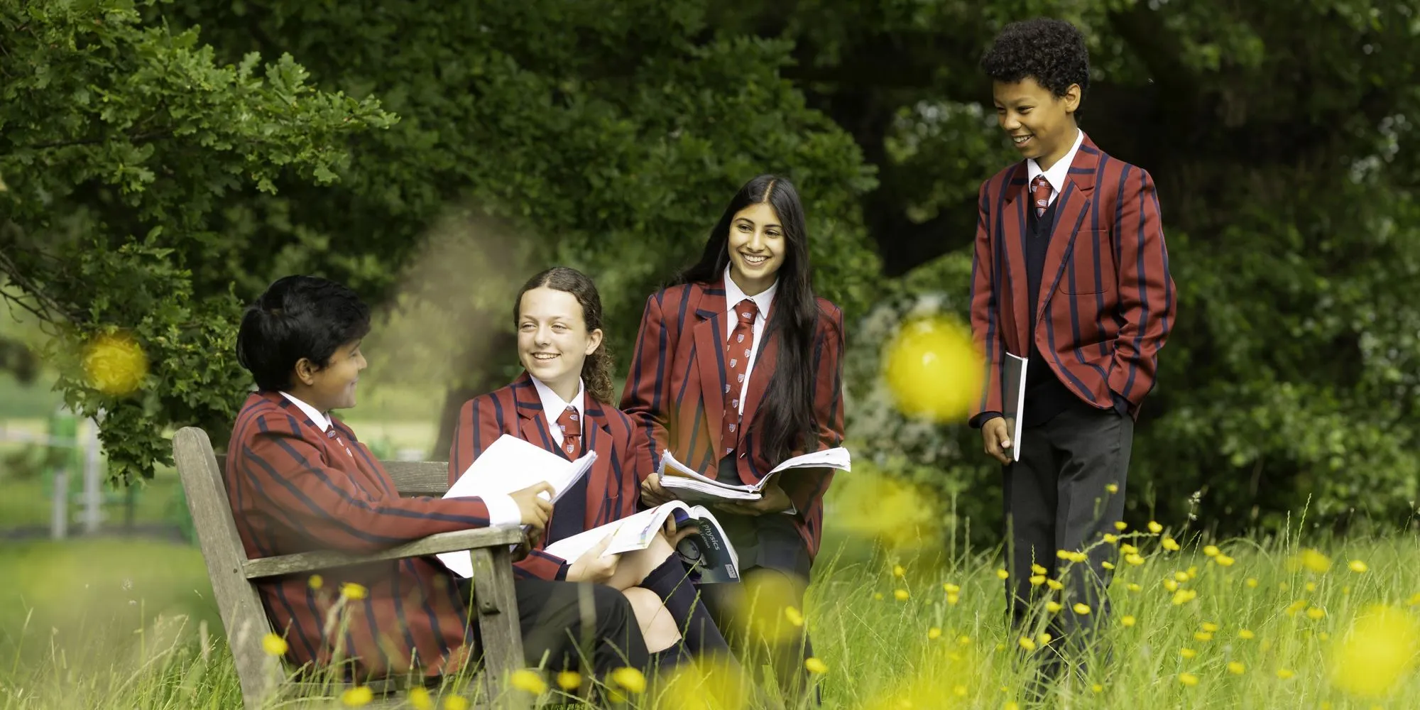 A group of children with the headteacher holding up exam results at Mill Hill County School.
