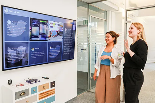 A big screen displaying a corporate social wall in the Walls.io office
