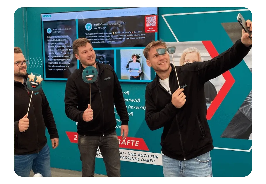 Event social wall on a screen with attendees taking a selfie with props