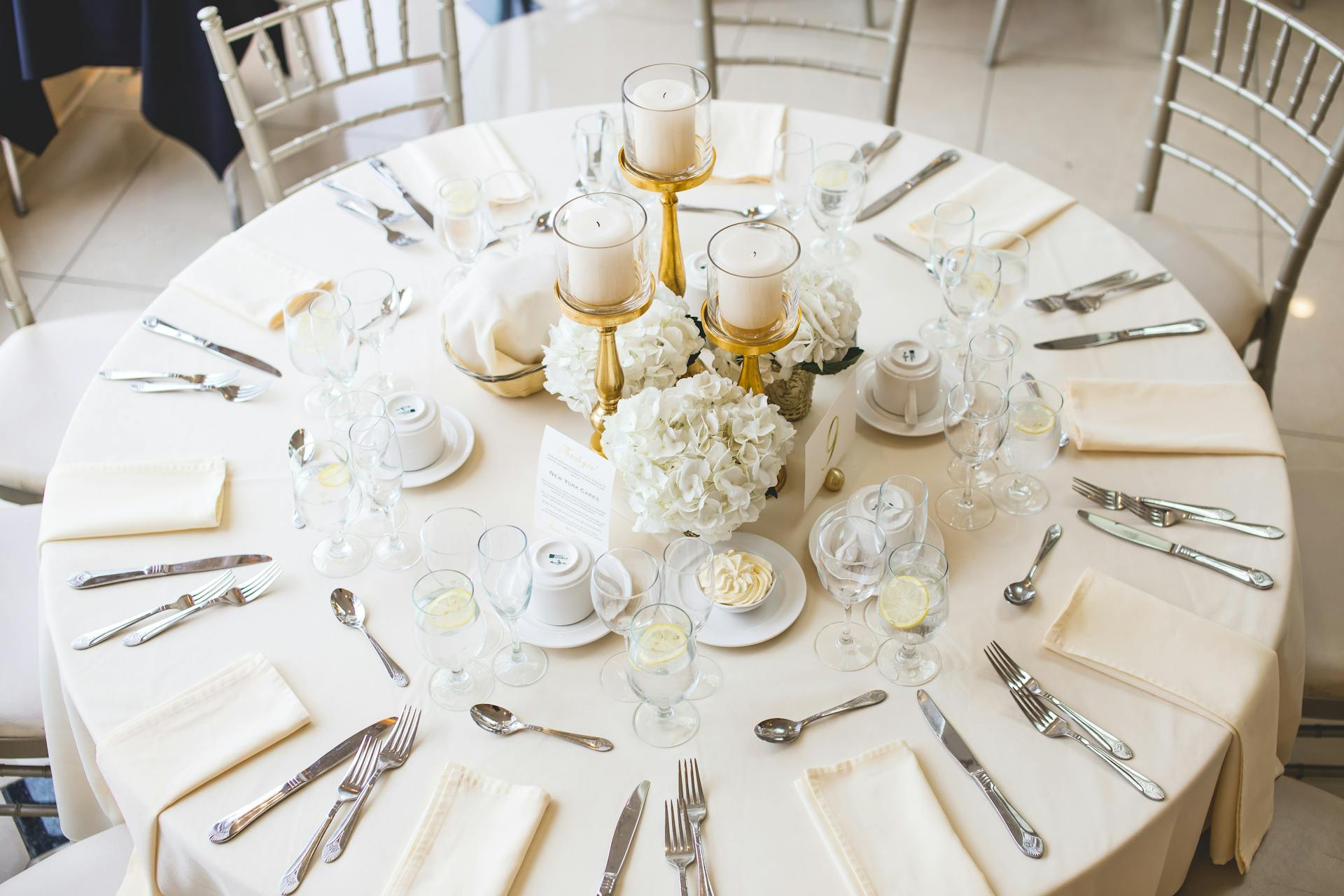 Round table at a wedding laid with flatware and centerpieces