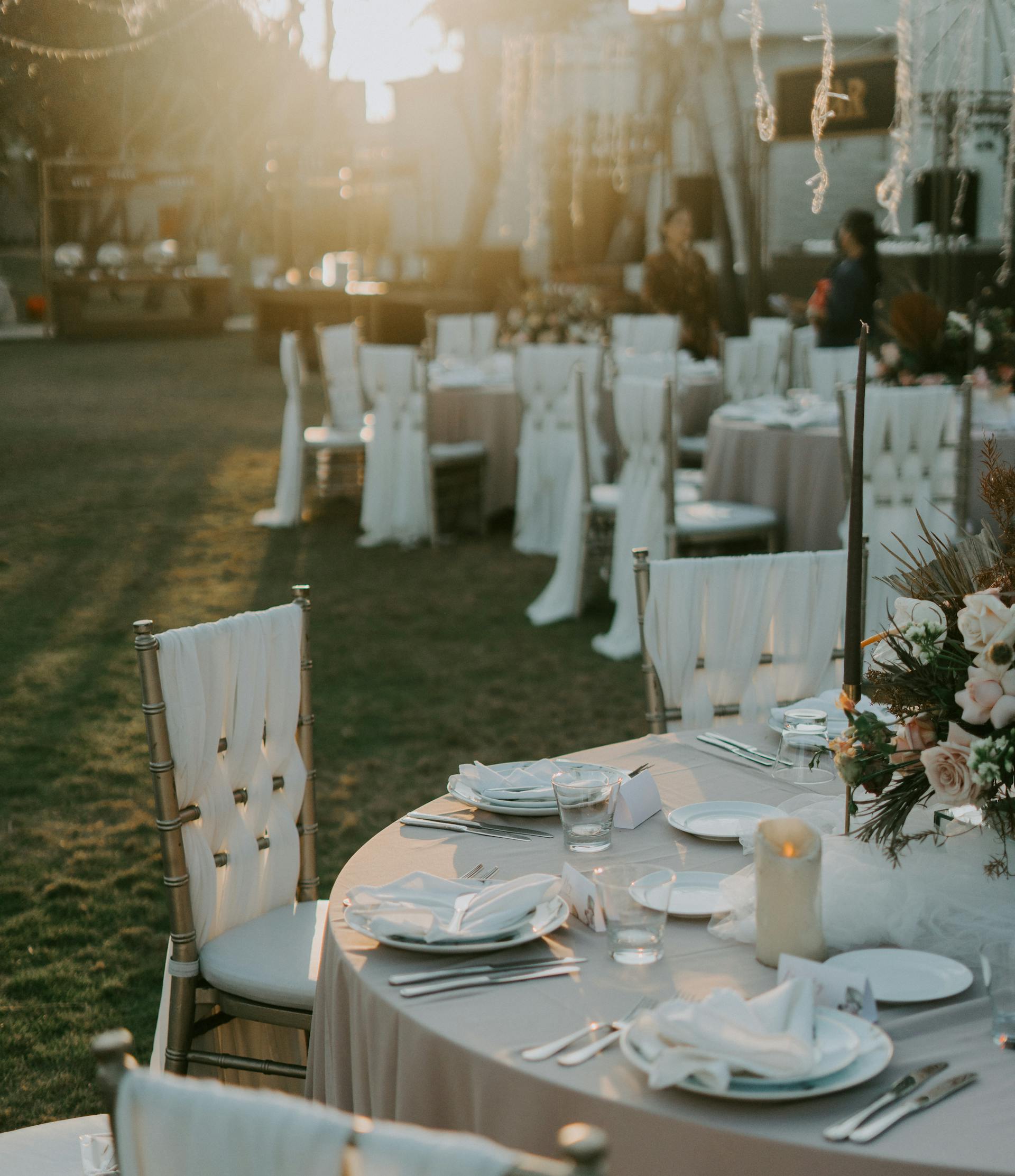 Round wedding table setting on a lawn at sunset