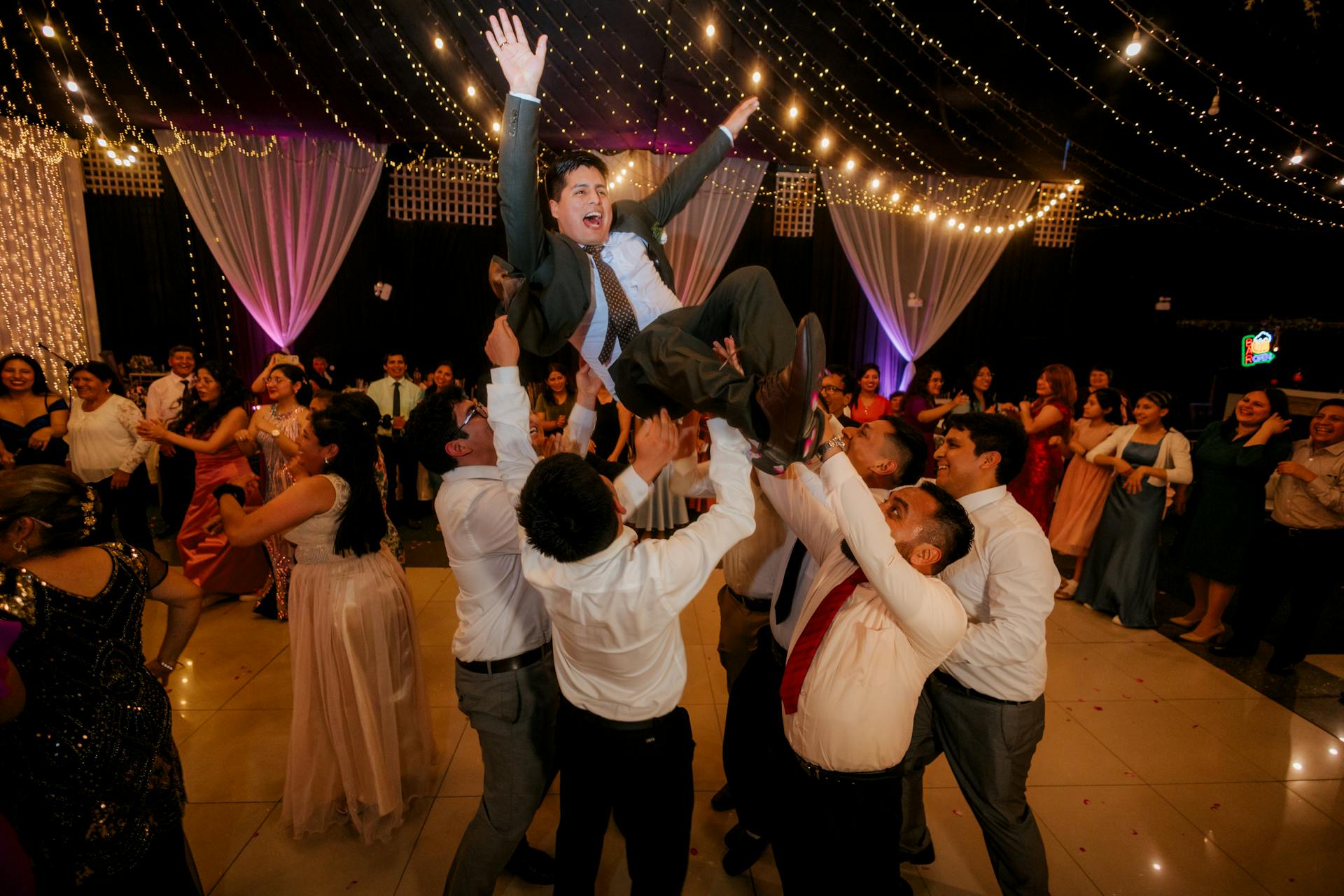 Wedding guests dancing and lifting the groom on the dance floor