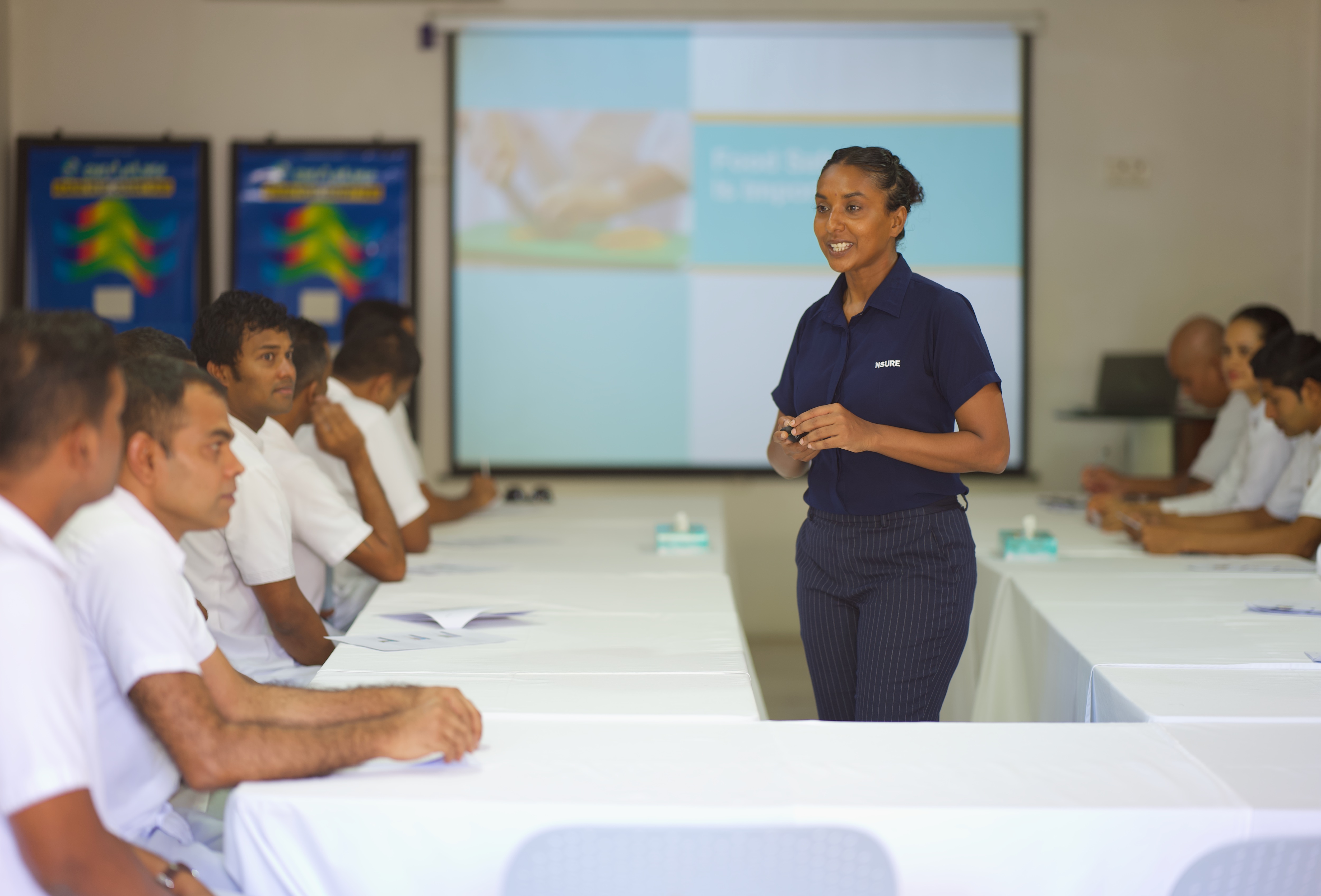 Team member Laisa presenting to staff in a large conference room
