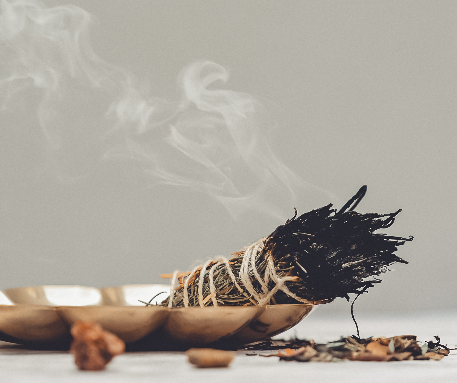 A bundle of dried cedar leaves being burned in a sacred smoke ritual to clear negative energy and purify a home.