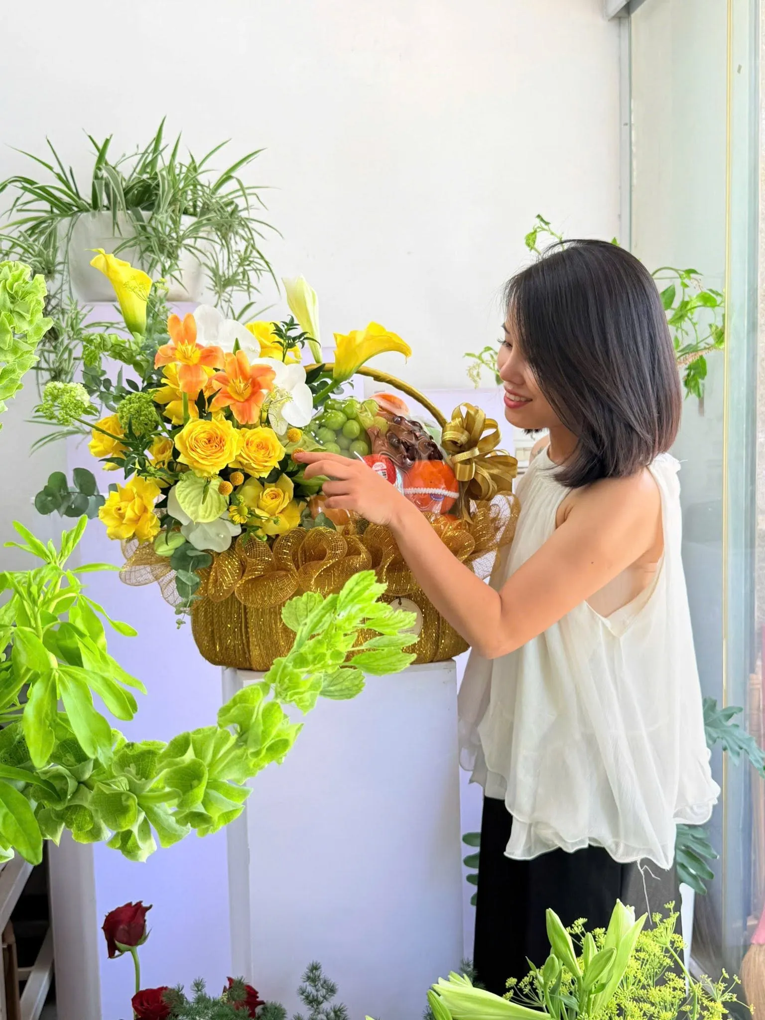 Cô gái chỉnh giỏ hoa vàng phối trái cây trên bục trắng tại Tân Thạnh, Long An