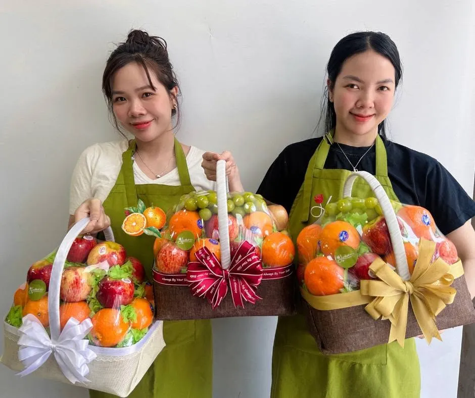 Hai nhân viên cầm ba giỏ trái cây thành phẩm tại Ayun Pa, Gia Lai