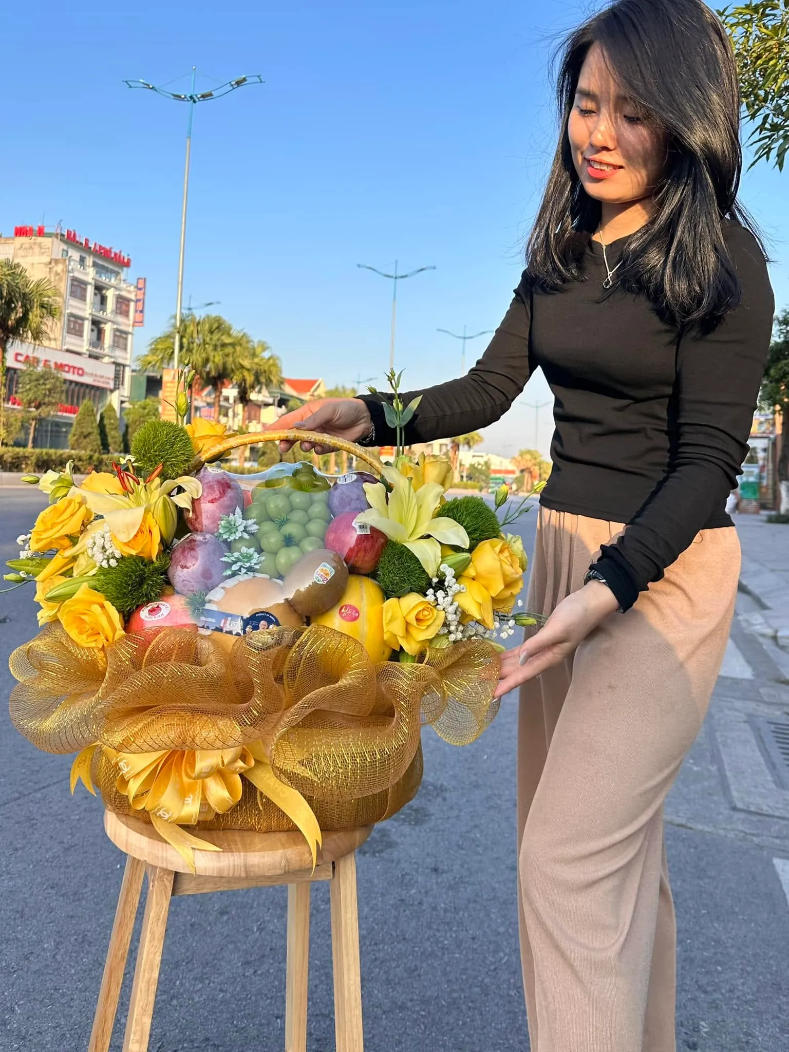 Cô gái chỉnh giỏ trái cây phối hoa vàng ngoài trời tại Huyện Côn Đảo