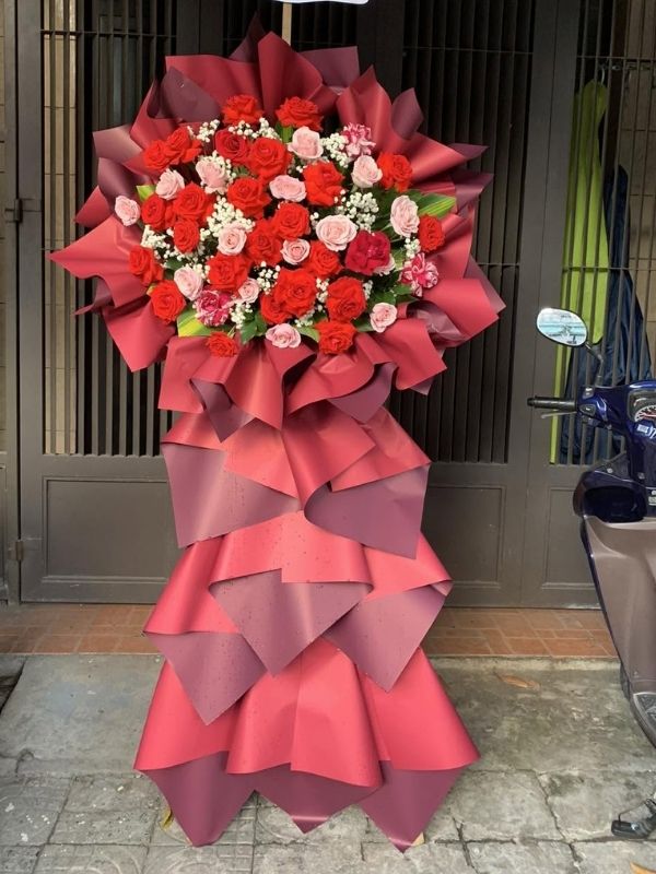 Khai Trương Vạn Sự là mẫu kệ hoa khai trương mang tone màu chủ đạo cam - san hô nổi bật, tượng trưng cho sự nhiệt huyết, năng động và tinh thần khởi đầu hưng thịnh — lựa chọn được nhiều khách hàng tin tưởng khi cần một lẵng hoa khai trương thật ấn tượng.

Thành phần hoa chính gồm cẩm chướng cam, hồng cam và đồng tiền cam, phối cùng dương xỉ, lá bạc và baby trắng để tôn lên tổng thể tươi tắn, hài hòa và tràn đầy sức sống cho không gian khai trương.

Sản phẩm được thiết kế theo dáng kệ hoa đứng 3 tầng bề thế, form dáng vững chãi, cân đối, phù hợp trưng bày ở những vị trí trang trọng, dễ gây ấn tượng ngay từ cái nhìn đầu tiên.

Chiều cao kệ hoa khoảng 1m8 – 2m tùy mẫu, đường kính chân đế 60 – 70cm, kích thước lý tưởng để đặt trước sảnh, cửa ra vào hoặc khu vực sự kiện mà không chiếm quá nhiều diện tích.

Đây là món quà thích hợp gửi tặng trong các dịp khai trương cửa hàng, công ty, spa, khách sạn, nhà hàng, văn phòng hay showroom, giúp chủ nhân buổi lễ thêm phần rạng rỡ và trang trọng.

Với thiết kế sang trọng, Khai Trương Vạn Sự là mẫu kệ hoa khai trương, lẵng hoa khai trương được yêu thích trong nhóm hoa khai trương sang trọng, hoa khai trương cao cấp dành cho khách hàng doanh nghiệp.

Sản phẩm gửi gắm thông điệp chúc mừng ý nghĩa: chúc công việc kinh doanh thuận buồm xuôi gió, làm ăn phát đạt, vạn sự hanh thông và ngày càng thịnh vượng. Dải băng rôn có thể tùy chỉnh nội dung lời chúc theo yêu cầu.

Liên hệ Shop Hoa Mãi Mãi ngay hôm nay để được tư vấn chọn mẫu phù hợp và đặt hoa giao nhanh tận nơi!