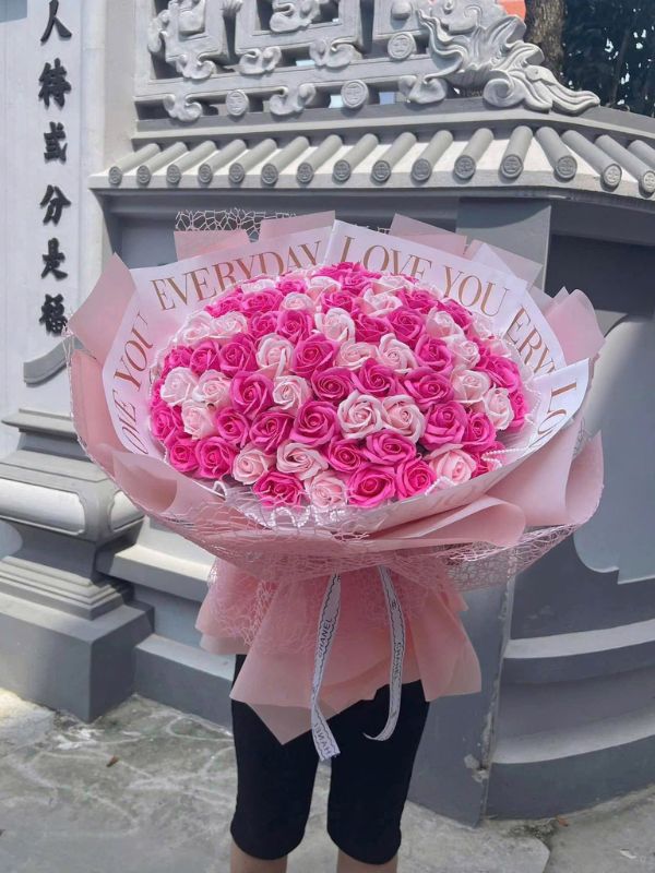 Màu sắc: hồng sen đậm pha hồng phấn. Dịp tặng: tặng mẹ, 8/3, 20/10, sinh nhật, mừng thọ. Loại sản phẩm: Hoa sáp.

Hoa Sáp Tặng Mẹ Sang Trọng phối hai sắc hồng: hồng sen đậm và hồng phấn nhạt xếp xen kẽ, nên mặt hoa có chiều sâu và không bị phẳng một màu. Giấy gói hồng nhạt in chữ nhũ vàng làm tổng thể nhìn chỉn chu, hợp với một món quà trang trọng.

Bó khá lớn với khoảng 80 đến 100 bông hồng sáp nhỏ kết dày thành vòm tròn đầy, phần cổ bó bọc lớp lưới ren hồng.

Cách gói theo kiểu bó tròn nhiều lớp, giấy in chữ nhũ vàng ôm quanh mặt hoa, thắt nơ ruy băng trắng có chữ ở cán. Bó cao khoảng 55 đến 60cm, đường kính mặt hoa chừng 40cm, cần hai tay để ôm nên lúc trao rất có không khí.

Món quà này dành cho mẹ, bà, mẹ chồng hoặc mẹ vợ trong dịp 8/3, 20/10, sinh nhật, mừng thọ, và cũng hợp để tặng cấp trên là nữ.

Anh chị gọi 0934.833.013 – 0907.473.357 hoặc nhắn Facebook Hoa Mãi Mãi để đặt, shop giao tận nhà đúng ngày.