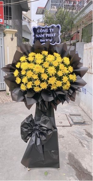 Màu sắc: vàng phối trắng. Dịp tặng: lễ viếng, lễ tang, lễ nhập quan, tiễn biệt, chia buồn. Loại sản phẩm: Hoa chia buồn / hoa tang lễ.

Kệ Hoa Viếng - HCB.22 là mẫu kệ hoa hình tam giác tang lễ được các nghệ nhân Hoa Mãi Mãi chăm chút tỉ mỉ từng chi tiết, phù hợp sử dụng trong lễ viếng, lễ truy điệu, lễ động quan hay giờ phút tiễn đưa người đã khuất về nơi an nghỉ cuối cùng.

Bảng màu vàng phối trắng chủ đạo mang đến sự cân bằng giữa nỗi buồn tiễn biệt và sự ấm áp, chân thành, giúp người gửi truyền tải trọn vẹn tấm lòng của mình.

Thành phần hoa chính gồm cúc đồng tiền vàng trắng và lan mokara vàng, được chọn lọc kỹ càng để giữ được độ tươi lâu, phối cùng hồng môn trắng, lá cau nhằm tạo nên tổng thể cân đối, mềm mại mà vẫn giữ được sự trang nghiêm cần có.

Kích thước hoàn thiện cao khoảng 1,8 – 2,0m, đường kính phần hoa chính 70 – 90cm, được tính toán để đảm bảo tỷ lệ cân xứng giữa phần khung/đế và phần hoa; có thể gia giảm kích cỡ theo không gian thực tế của tang lễ.

Thông điệp gửi viếng: gắn kèm bảng kính viếng trang trọng, nội dung linh hoạt theo yêu cầu như "Thành kính phân ưu", "Xin chia buồn cùng gia quyến" hoặc lời nhắn riêng của quý khách.

Tùy biến mẫu theo yêu cầu: Với nhiều năm kinh nghiệm trong lĩnh vực hoa tang lễ, Hoa Mãi Mãi có thể điều chỉnh linh hoạt mẫu hoa theo yêu cầu riêng của từng gia đình, cam kết giao hoa tận nơi, đúng giờ và luôn giữ được độ tươi mới.